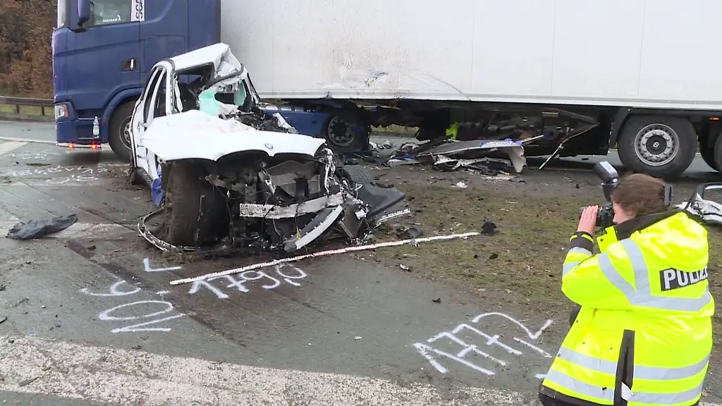 Eine-Polizistin-fotografiert-ein-total-zerstoertes-Fahrzeug-an-einer-Unfallstelle