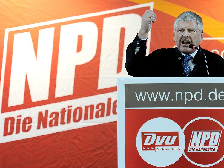 NPD-Chef Udo Voigt hinter den beiden Logos der Parteien. Die NPD trägt jetzt den Zusatz "Die Volksunion".