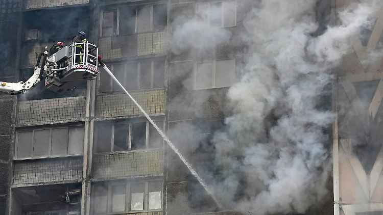 Feuerwehrleute löschen ein Feuer in einem Wohnhaus nach einem russischen Angriff. 
