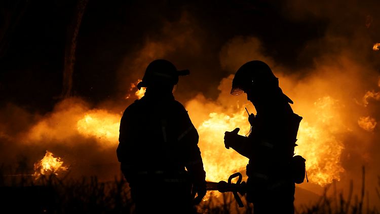 Feuerwehrleute stehen in Charkiw vor dem Flammenmeer, in dem sieben Menschen starben.