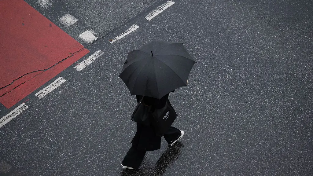 Mit-einem-Schirm-schuetzt-sich-eine-Passantin-in-Frankfurt-vor-dem-stroemenden-Regen