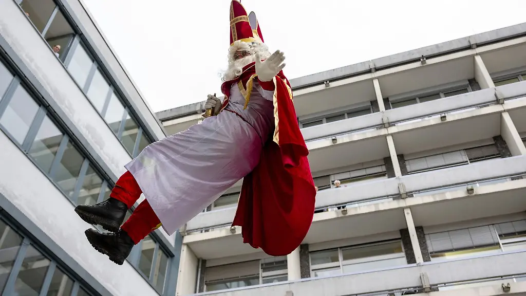Ein-als-Nikolaus-verkleideter-Hoehenretter-seilt-sich-an-einer-Wand-des-Klinikums-Mutterhaus-ab