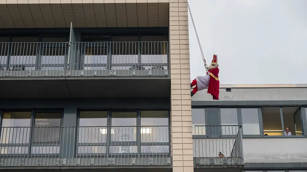 Ein-als-Nikolaus-verkleideter-Hoehenretter-der-Feuerwehr-seilt-sich-an-einer-Wand-ab