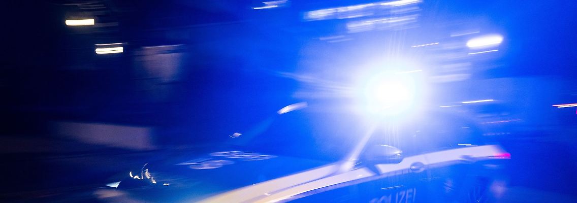 Ein Polizeifahrzeug fährt mit Blaulicht an einem Gebäude vorbei.