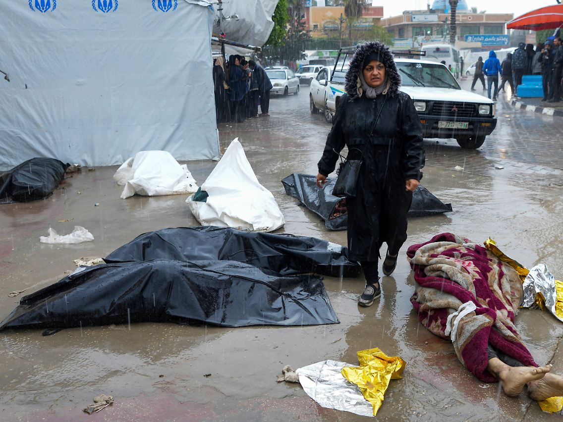 Eine Frau geht an Leichen vorbei - Alltag in Gaza.