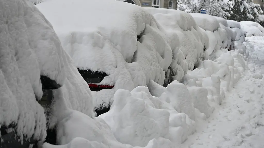 Eine-dicke-Schneeschicht-liegt-auf-parkenden-Autos-in-Muenchen
