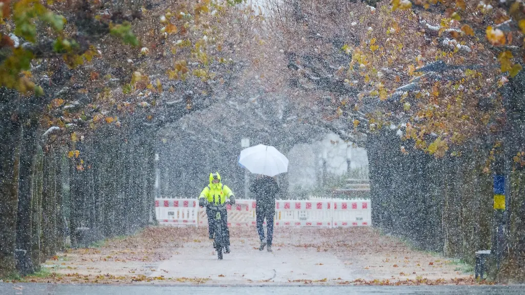 Ein-Radfahrer-und-ein-Fussgaenger-sind-bei-dichtem-Schneetreiben-am-Rheinufer-in-Mainz-unterwegs