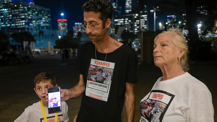 Angehörige von Jonathan Samerano, der am 7. Oktober von der Hamas entführt wurde, zeigen während einer Demonstration in Tel Aviv sein Foto auf einem Telefon.