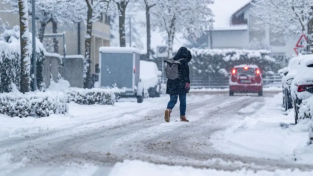 Eine-Frau-geht-auf-einer-mit-Schnee-bedeckten-Strasse
