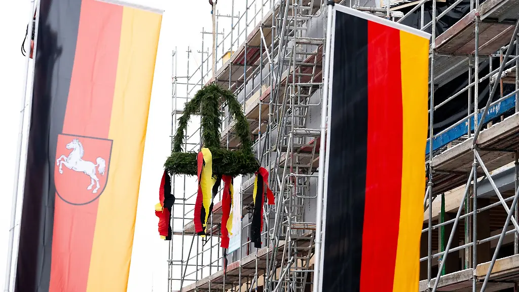 Der-Richtkranz-ist-beim-Richtfest-fuer-das-Museum-Friedland-hinter-Flaggen-zu-sehen