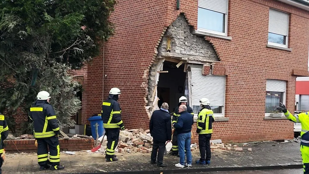 Einsatzkraefte-stehen-vor-einem-grossen-Loch-in-einer-Hauswand-das-ein-Lastwagen-verursacht-hat
