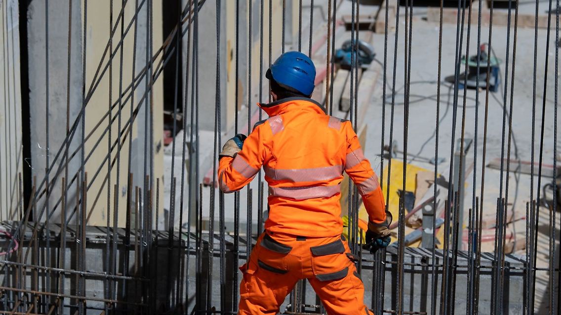 Ein Bauarbeiter verlegt auf einer Baustelle Stahlmatten.