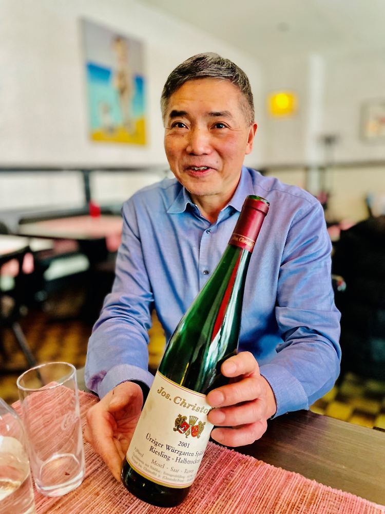 Der Berliner Gastronom Jianhua Wu mit einem Wein seines mittlerweile geschlossenen deutschen Lieblingsweingutes "Jos. Christoffel jun." Der Vorname Jianhua bedeutet übrigens in maoistischer Tradition "Fortschritt" - und der ist Wu in puncto "Wine Pairing" hervorragend gelungen.
