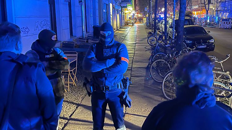 Polizisten sichern den Eingang des Hauses, in dem die Razzia stattfindet. 