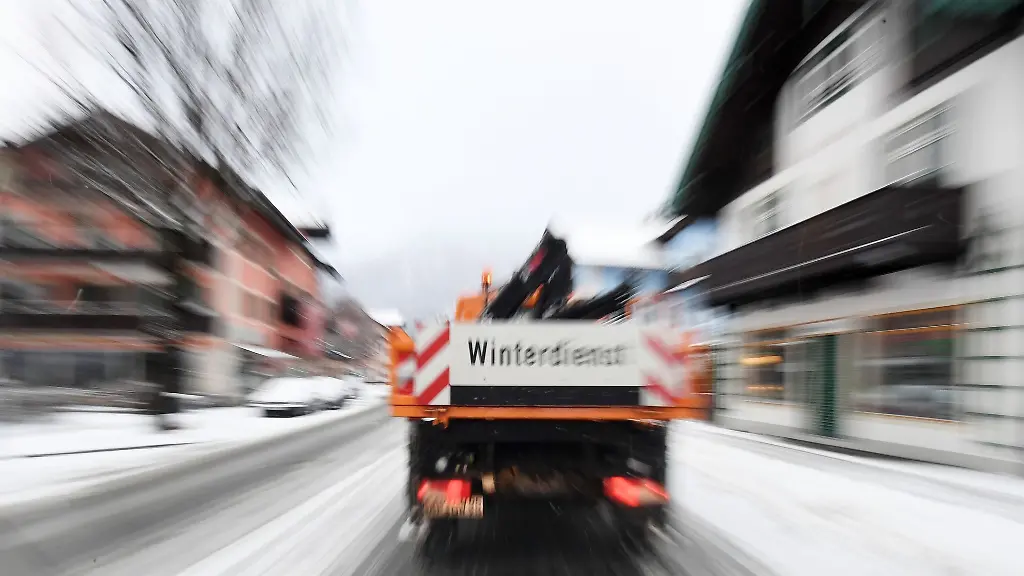 Ein-Fahrzeug-des-Winterdienstes-faehrt-ueber-eine-Strasse