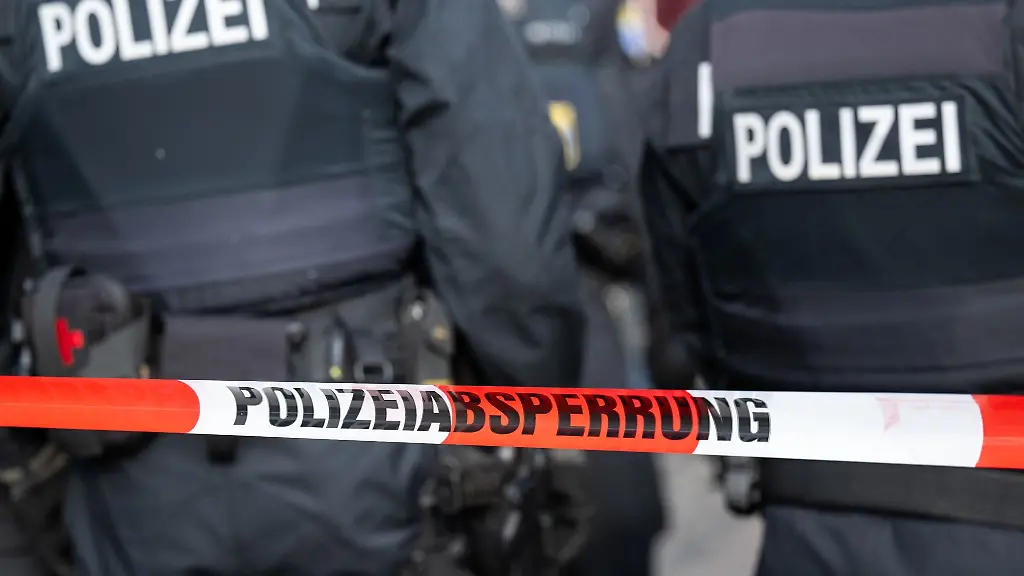Polizisten-stehen-hinter-einem-Polizei-Flatterband