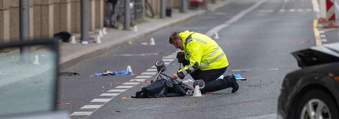 Ein Polizist kniet an der Unfallstelle neben dem zerstörten Kinderwagen.