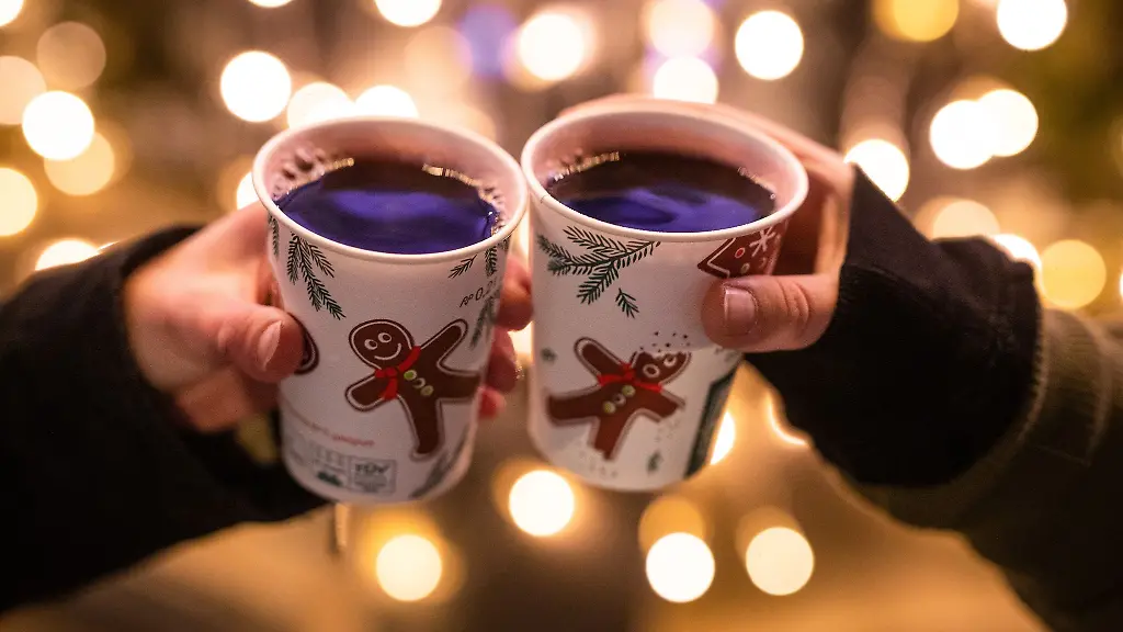 Zwei-Besucherinnen-eines-Weihnachtsmarktes-stossen-mit-Gluehwein-an