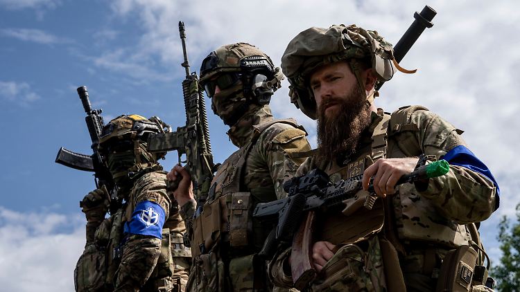 Kämpfer des "Russischen Freiwilligenkorps" stehen während einer Pressekonferenz im Mai 2023 in der ukrainischen Region Sumy auf einem Schützenpanzer. 