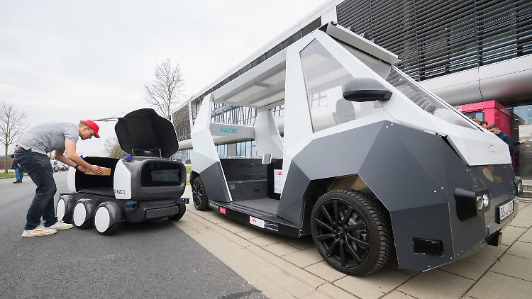 Ein Mitarbeiter vom Institut für Fahrzeugtechnik der Technischen Universität Braunschweig packt Pakete in autonome Lieferfahrzeuge. 