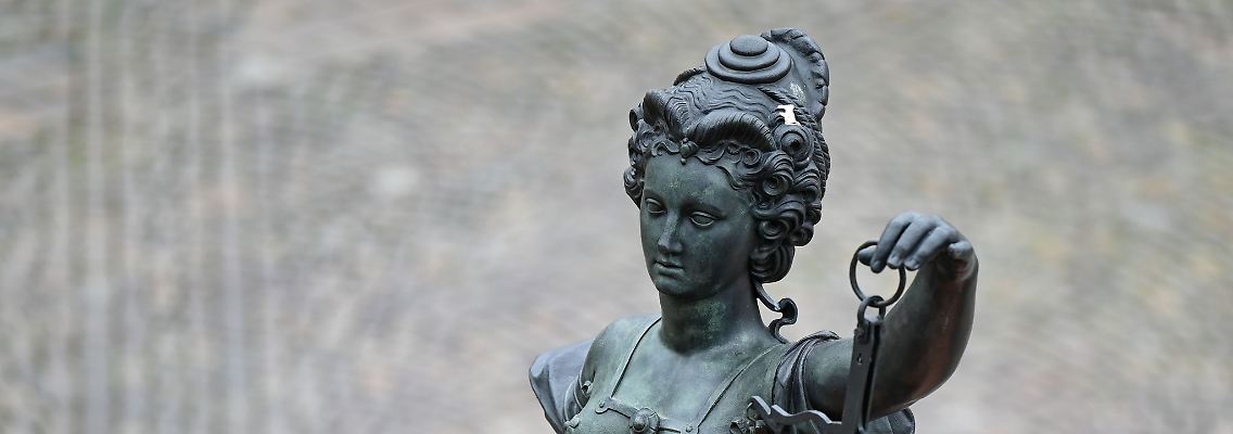 Eine Statue der Justitia hält eine Waage und ein Schwert in der Hand.