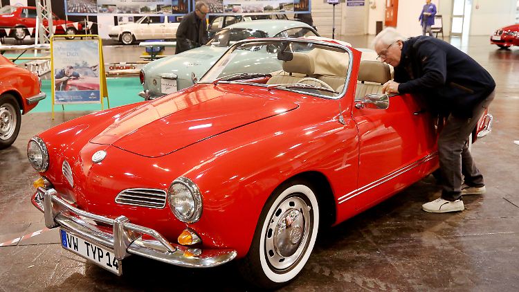 Ein Karmann Ghia weckt das Interesse eines Besuchers bei der Oldtimermesse Techno Classica.