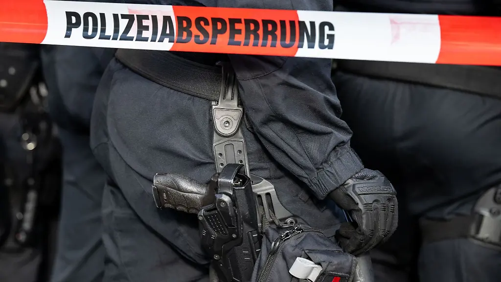 Polizisten-stehen-hinter-einem-Polizei-Flatterband