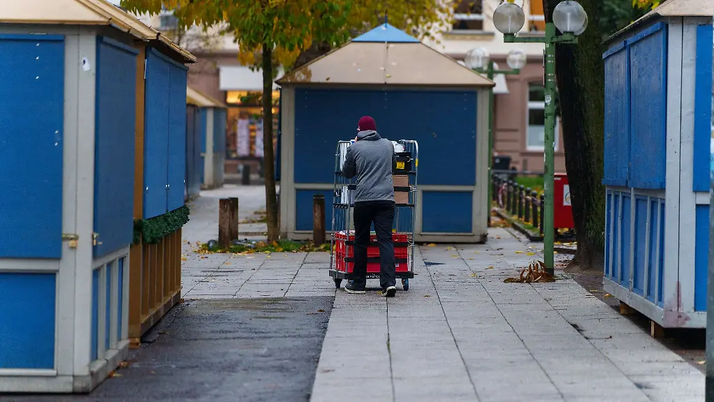 Ein-Mann-rollt-Ware-zu-einer-Verkaufsbude-auf-dem-Weihnachtsmarkt