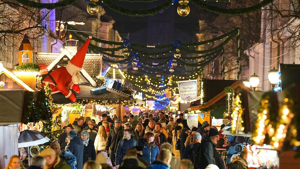 Passanten-gehen-in-der-Brandenburger-Strasse-zwischen-den-Buden-des-Weihnachtsmarktes-in-der-Innenstadt-entlang