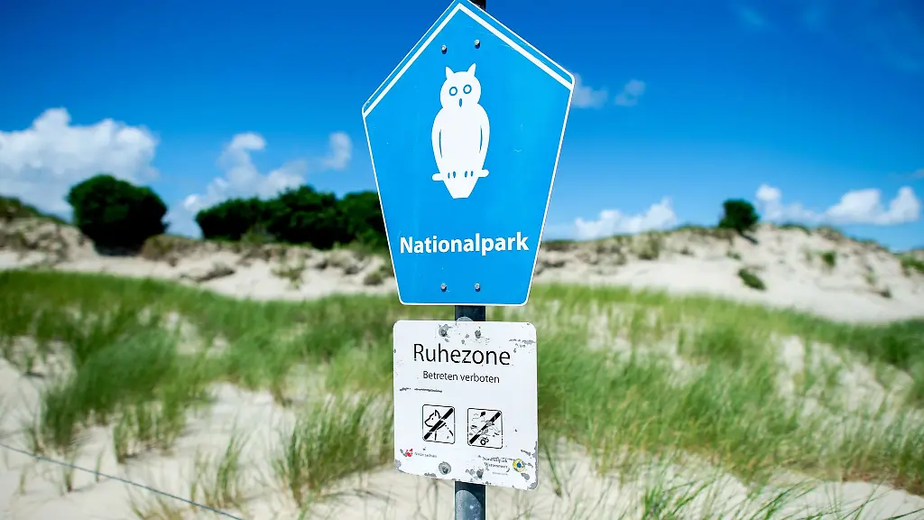 Ein-Schild-mit-der-Aufschrift-Nationalpark-steht-vor-der-Duenenlandschaft-am-Ostende-der-Insel-Norderney