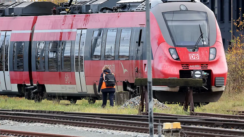 Eine-Zugbegleiterin-geht-in-der-Naehe-des-Hauptbahnhofs-zu-einem-abgestellten-Zug