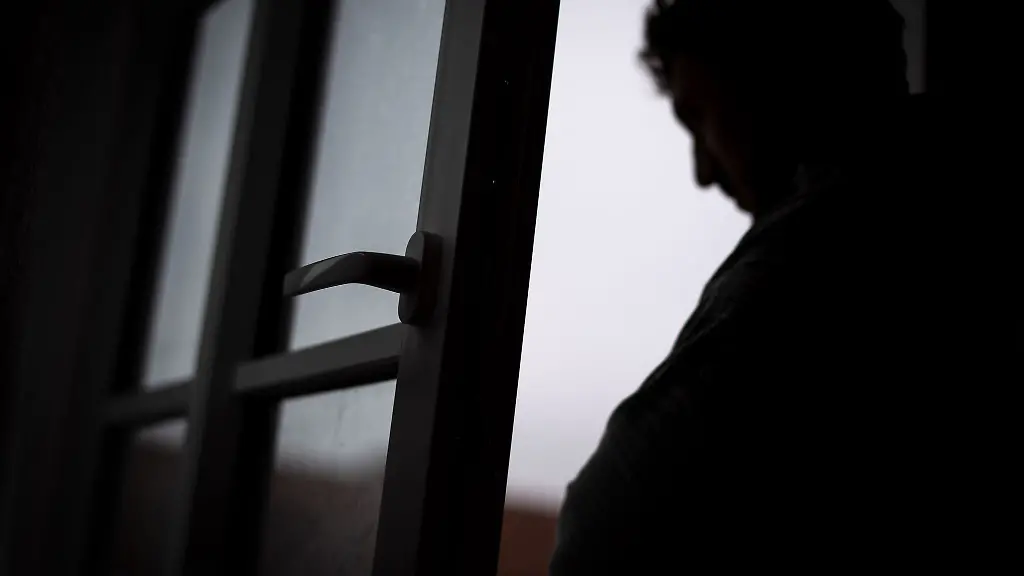 Ein-Mann-steht-am-offenen-Fenster-seiner-Wohnung