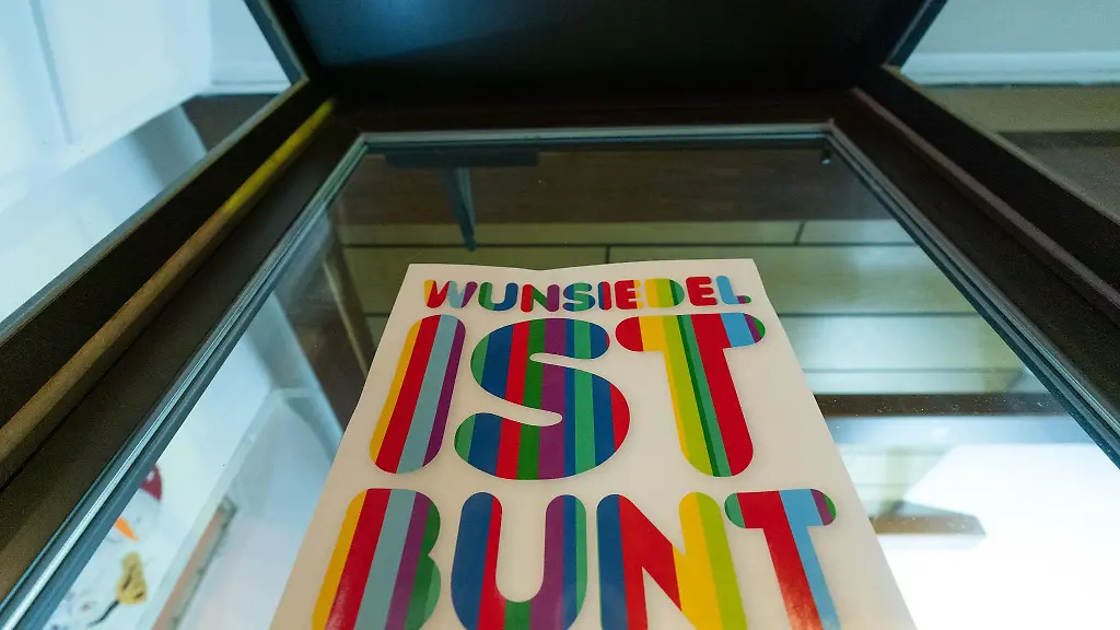 An-einer-Fensterfront-eines-Geschaeftes-ist-ein-Plakat-mit-der-Aufschrift-Wunsiedel-ist-bunt-angebracht