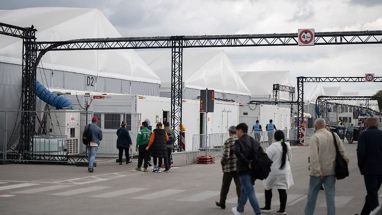 Bewohner und Mitarbeiter gehen im Ankunftszentrum am ehemaligen Flughafen Tegel in Richtung der Leichtbauhallen.