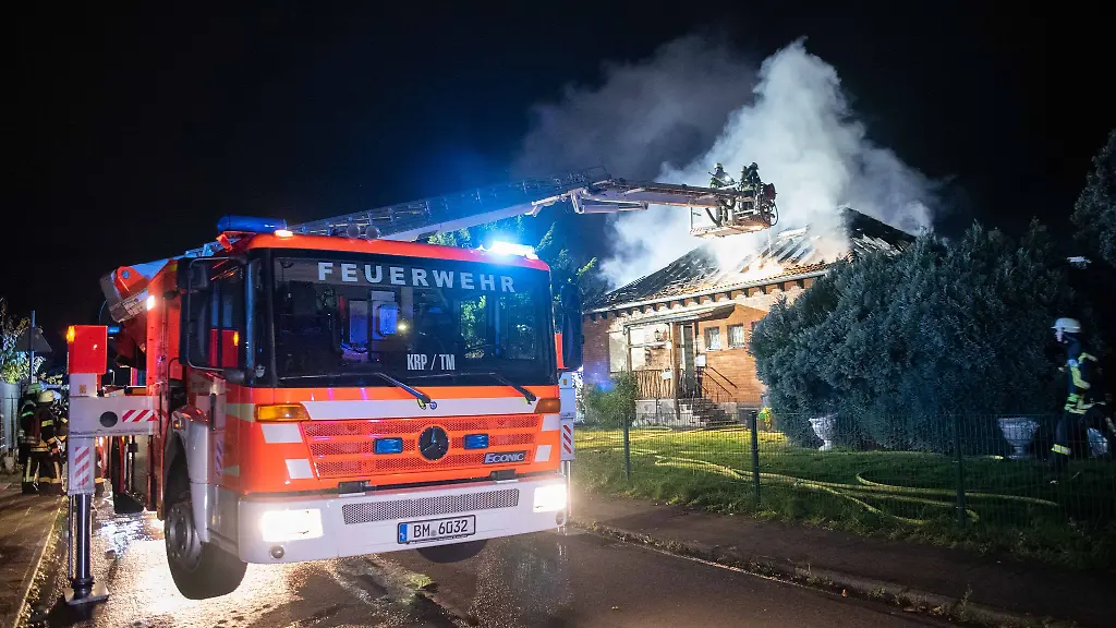 Feuerwehrleute-sind-ueber-eine-Drehleiter-an-einem-brennenden-Haus-im-Einsatz