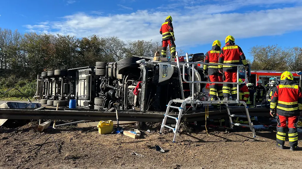 Einsatzkraefte-der-Feuerwehr-stehen-nach-einem-Unfall-an-einem-Lastwagen-auf-der-Autobahn-9-bei-Manching