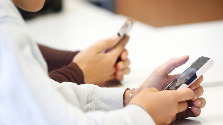 Schülerinnen benutzen während eines Vortrags über die Anwendungen von Künstlicher Intelligenz ihr Smartphone im Unterricht.