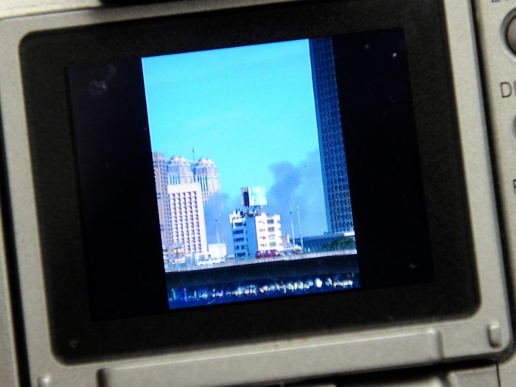 Urlaubsfoto: Eine Touristin zeigt am Sonntag im Flughafen München nach ihrer Ankunft aus Ägypten ein Foto aus Kairo mit einer Rauchwolke neben Hochhäusern.