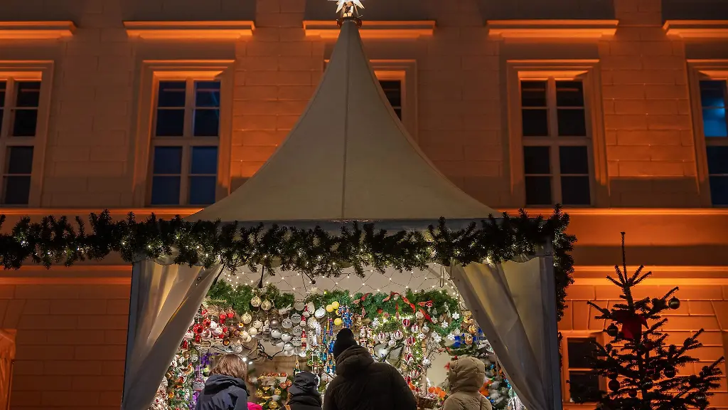 Besucher-eines-Weihnachtsmarktes-stehen-an-einem-Verkaufsstand-fuer-Christbaumschmuck