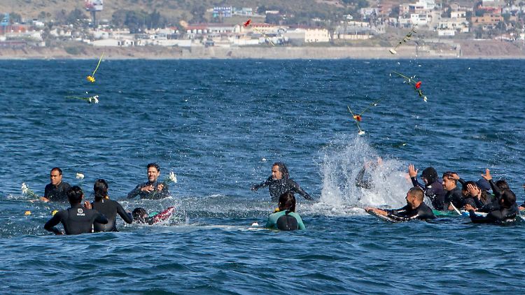 Während einer Gedenkfeier für drei vermisste ausländische Surfer werden Blumen ins Meer geworfen.