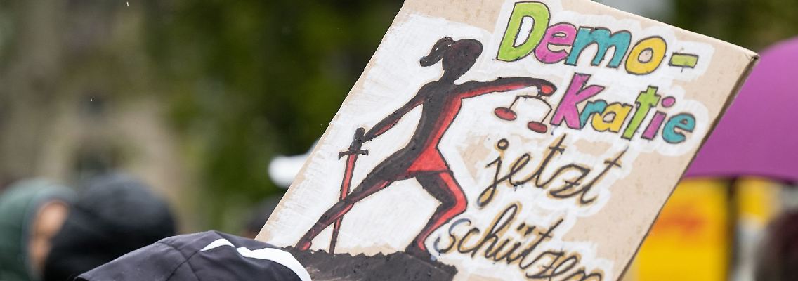 "Demokratie jetzt schützen" ist auf dem Schild einer Teilnehmerin einer Demo gegen rechts zu lesen.