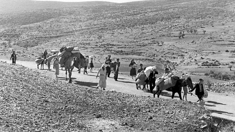 Arabische Flüchtlinge gehen mit ihren Kindern und Habseligkeiten im Gepäck am 9. November 1948 auf einer staubigen Straße von Jerusalem in den Libanon. Die Staatsgründung Israels war 1948 für Hunderttausende von Palästinensern mit Vertreibung und dem Verlust von Heimat verbunden.