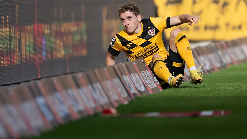 Dynamos-Luca-Herrmann-sitzt-in-der-Bandenwerbung-In-Saarbruecken-rutschten-er-und-seine-Mitspieler-oefter-ueber-den-Rasen