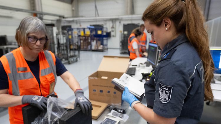Eine Zollbeamtin prüft den Inhalt eines Paketes in einem DHL-Verteilzentrum. 