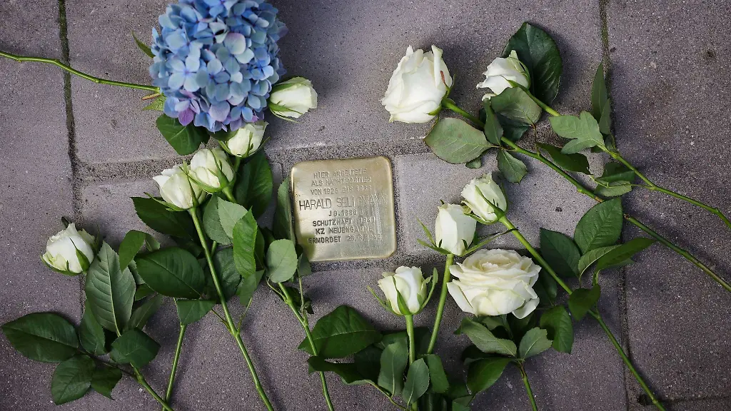 Rosen-und-andere-Blumen-liegen-neben-einem-frisch-verlegten-Stolperstein-vor-dem-Hotel-Vier-Jahreszeiten
