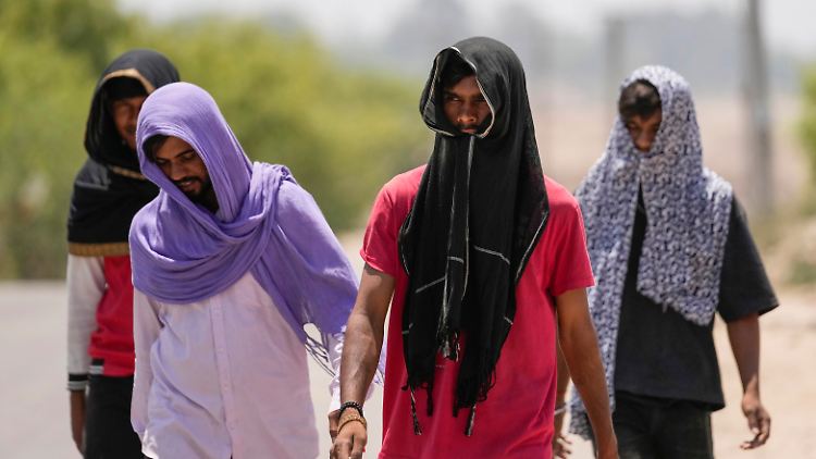 Im indischen Jammu bedeckten Männer ihre Köpfe, um sich vor der Hitze zu schützen.