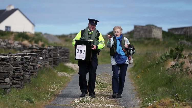 Gewählt wird auch am geografischen Rande Europas: Hier bringen ein Polizist und die örtliche Wahlverantwortliche eine Wahlurne ins Wahllokal auf der irischen Insel Inishbofin (Bild von 2019). In Irland findet die Wahl bereits am Freitag statt.