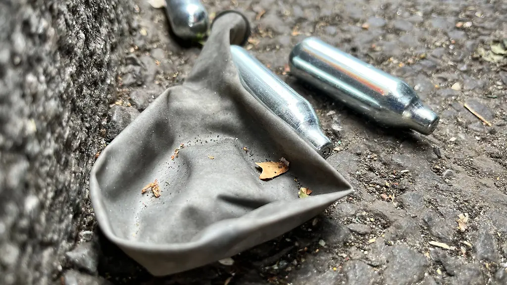 Auf-einer-Strasse-liegen-mehrere-Gaspatronen-und-ein-Luftballon