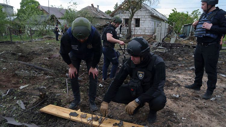 Ein ukrainischer Polizeibeamter und ein Staatsanwalt inspizieren Bruchstücke einer Gleitbombe nach einem russischen Luftangriff auf ein Wohnviertel in Charkiw. 