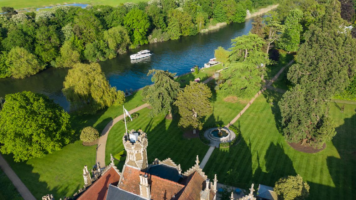 Diese Drohnenaufnahme zeigt: Die Themse schlängelt sich durch eine liebliche Landschaft mit historischen Schlössern und Herrenhäusern. Hier ist das Oakley Court Hotel zu sehen.